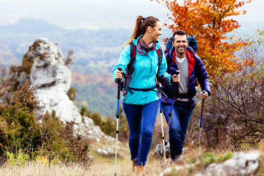 A man and a woman are hiking up a mountain side.
